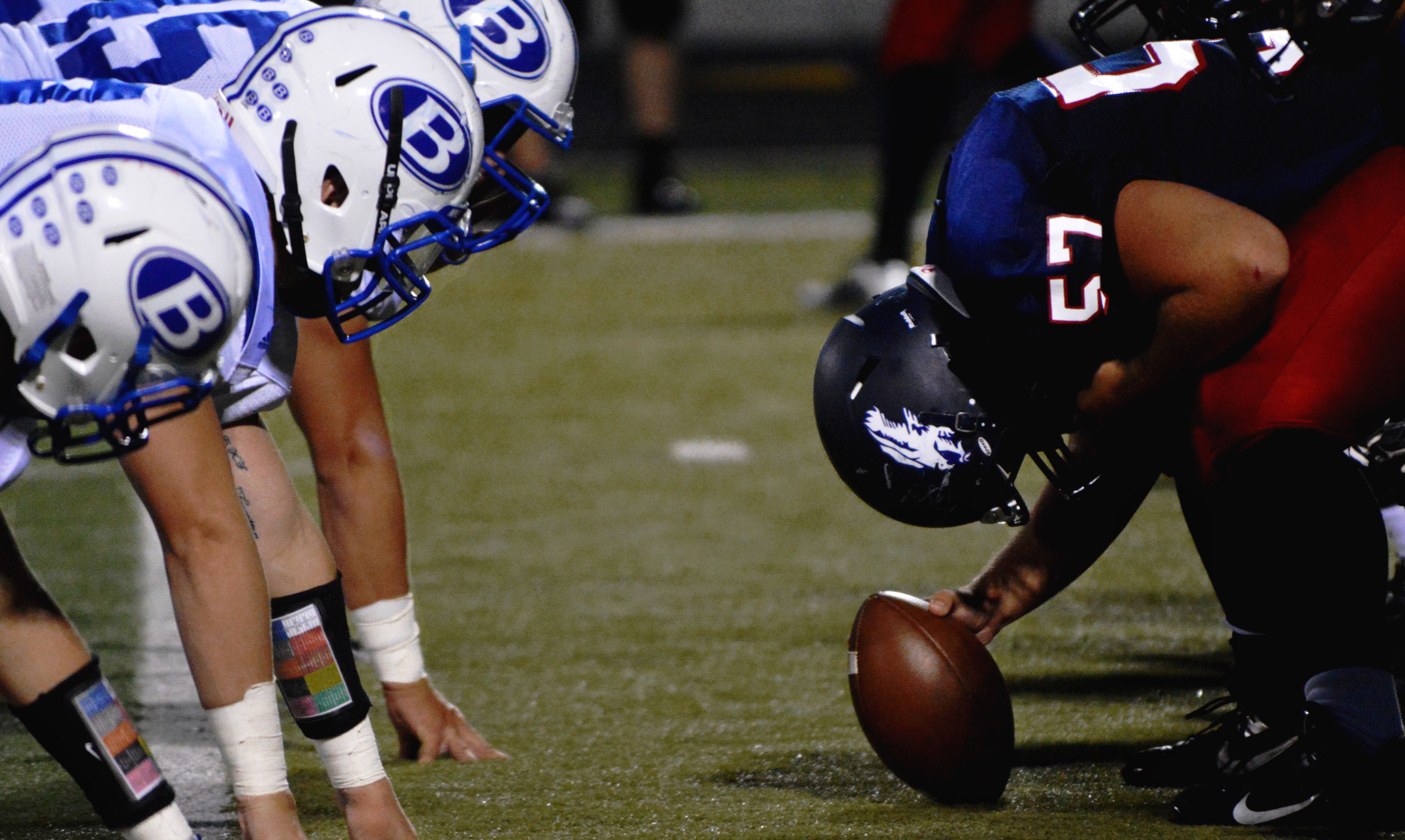 Two different American Football teams facing each other on the field, about to kick off the game.